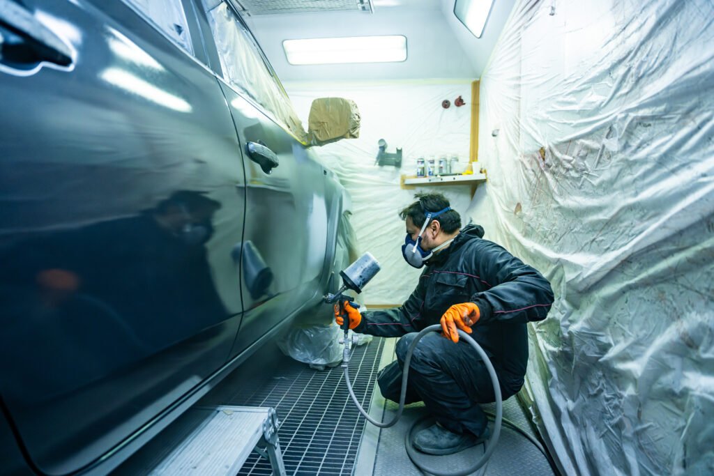 auto body mechanic spraying car in paint shop